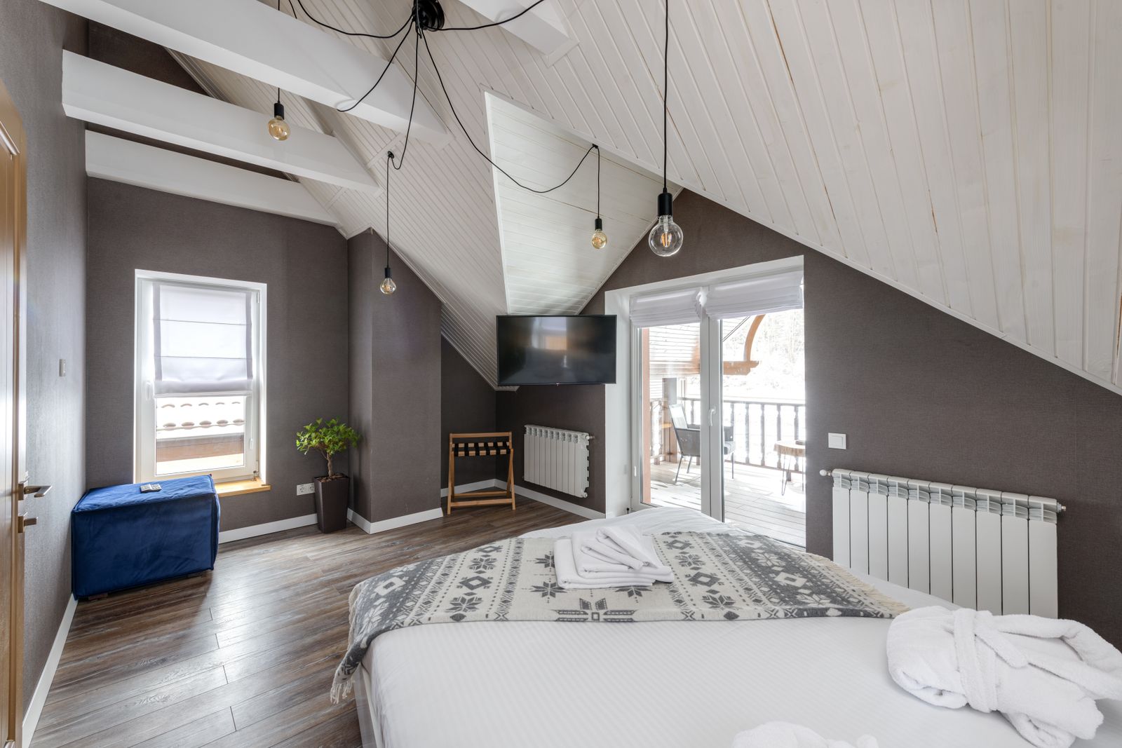 Um quarto moderno com uma cama grande, acesso a varanda e iluminação estilosa.